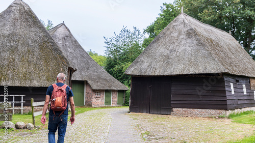 Male senior tourist with backpack walking along Orvelte picturesque monumental little town in Drenthe in The Netherlands. photo