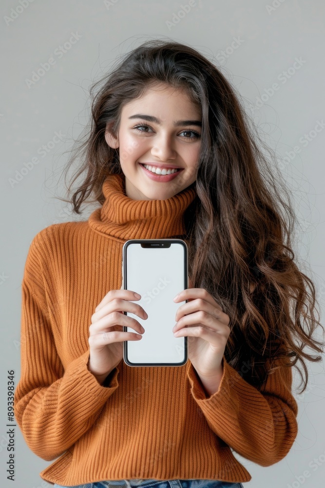 Cheerful Young Woman Holding Smartphone with Blank Screen in Casual Outfit Cheerful Young Woman Holding Smartphone with Blank Screen in Casual Outfit