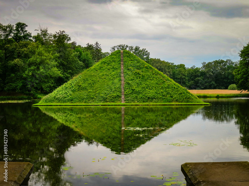 Ein in einem See angelegter pyramidenförmig angelegter  Grabhügel oder Tumulus; Spiegelung im Wasser vor dunklen Regenwolken photo