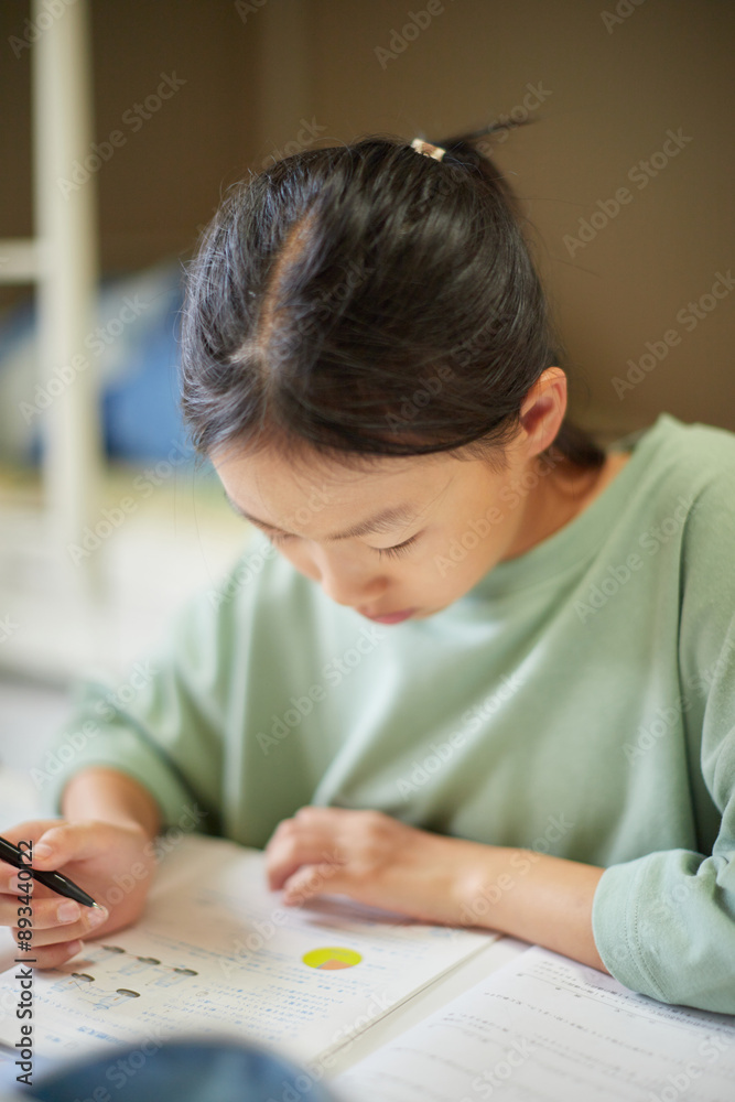 夏休み中の小学生の子供が家で宿題をする様子