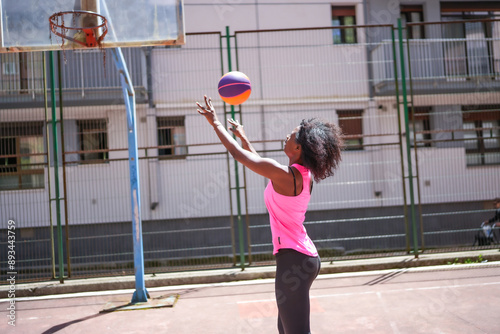 Arican woman throwing basketball ball in a outdoor court photo