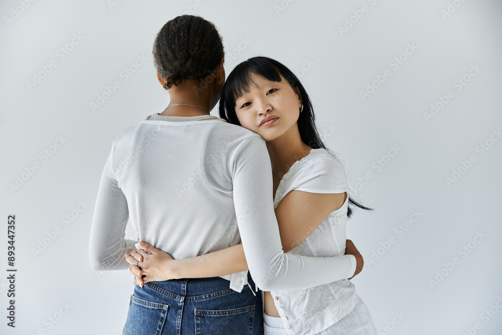 Two young women, lesbian couple, share a tender embrace against a white background. Two young women, lesbian couple, share a tender embrace against a white background.
