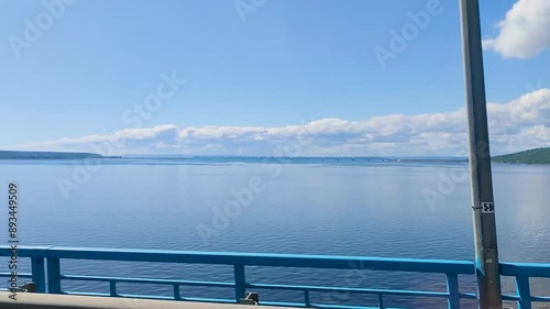Train, going through bridge. Window view overlooking vast river, showcasing a tranquil and picturesque scene on a bright, sunny day. Copy space