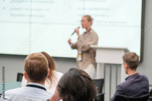 Speaker giving presentation at business conference while audience listens attentively. Professional development and networking