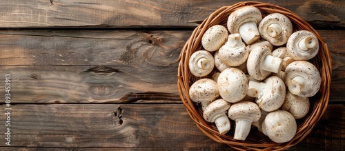 Freshly cut white mushrooms ideal for various dishes are displayed on a wooden background in a brown basket Top view with copy space image available