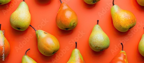 Colorful fruit pattern or background with pears arranged in a design on an orange backdrop perfect for a copy space image photo