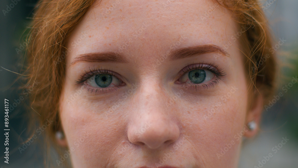 Close up beautiful smiling young Caucasian ginger woman face female lady girl slowly wide opening bright blue eyes looking camera outside city urban street. Clear vision makeup eyesight ophthalmology Close up beautiful smiling young Caucasian ginger woman face female lady girl slowly wide opening bright blue eyes looking camera outside city urban street. Clear vision makeup eyesight ophthalmology
