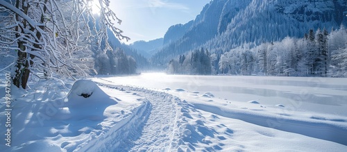A picturesque winter scene showing a square trail alongside a frozen lake in a snow covered valley with a serene and tranquil ambiance ideal for a copy space image