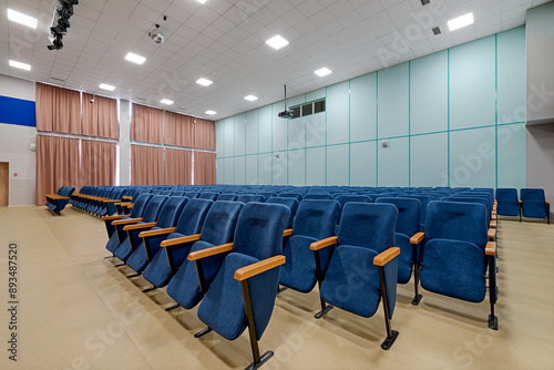 Rows of blue chairs in an empty auditorium hall. Conference room interior with chairs