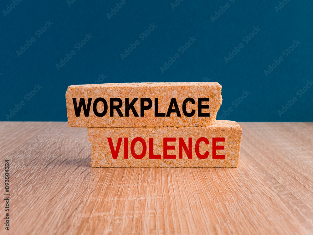 Concept red words WORKPLACE VIOLENCE on brick blocks. Beautiful blue background, wooden table. Business concept.