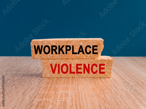 Obraz na płótnie Concept red words WORKPLACE VIOLENCE on brick blocks. Beautiful blue background, wooden table. Business concept. w salonie