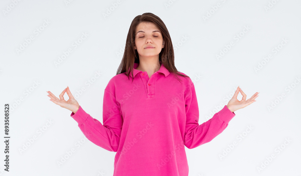 Mindful peaceful woman meditates indoor, keeps hands in mudra gesture, has eyes closed, tries to relax after long hours of working, holds fingers in yoga sign, isolated on white wall Mindful peaceful woman meditates indoor, keeps hands in mudra gesture, has eyes closed, tries to relax after long hours of working, holds fingers in yoga sign, isolated on white wall