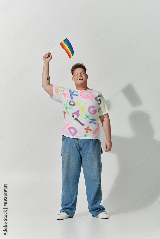A young man smiles joyfully, holding a rainbow flag aloft. A young man smiles joyfully, holding a rainbow flag aloft.