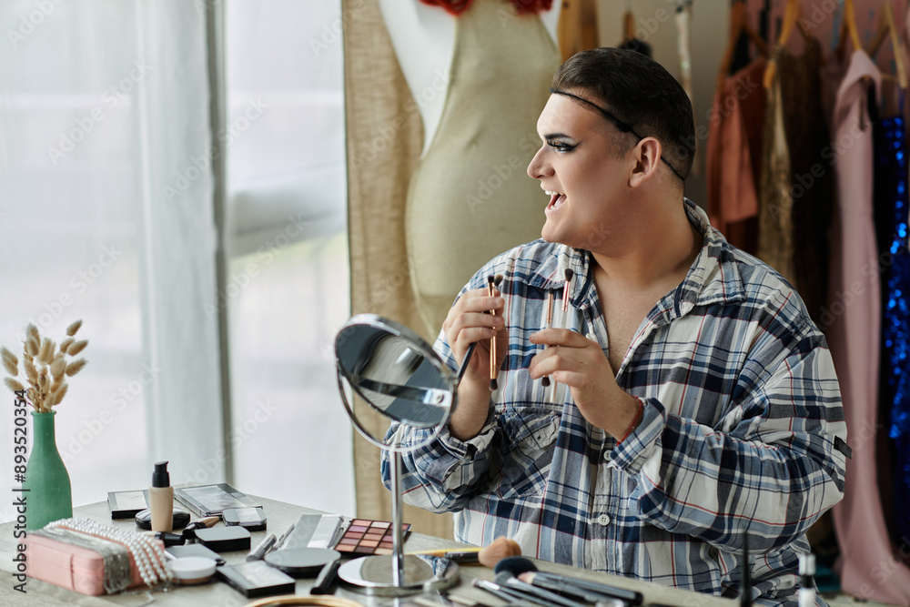 A man in a plaid shirt applies makeup in front of a mirror, surrounded by beauty products. A man in a plaid shirt applies makeup in front of a mirror, surrounded by beauty products.