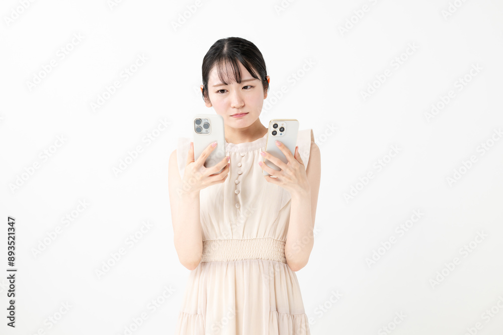 スマホを2台持って悩む女性 スマホを2台持って悩む女性