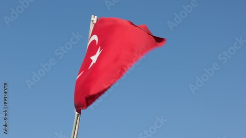 The Turkish flag waves proudly in the wind against a clear blue sky. Turkish flag waving in the wind