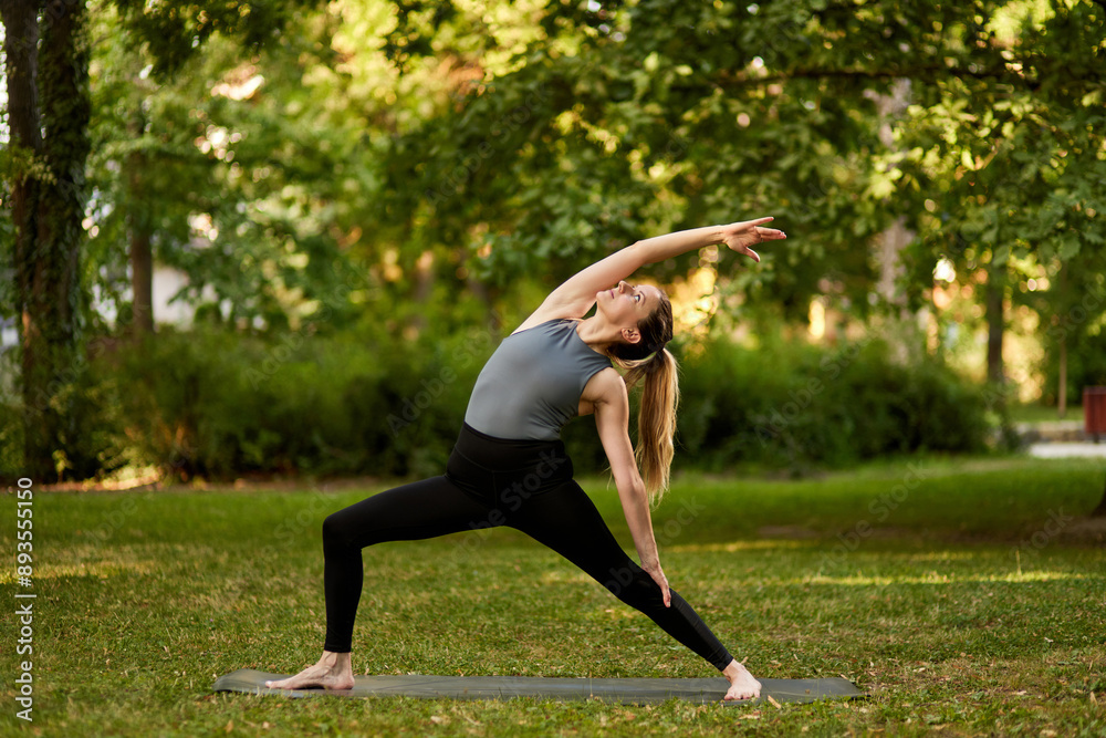 Fototapeta premium Woman practicing yoga in a park on a sunny day