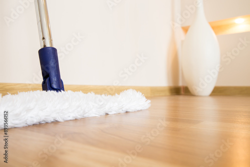 Wooden floor with white mop, cleaning service concept