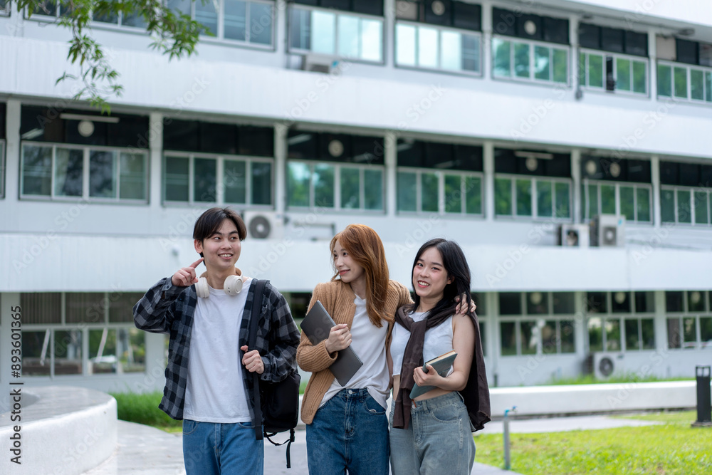 Three young people are walking down a sidewalk in front of a large building Three young people are walking down a sidewalk in front of a large building