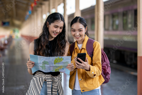 Two women are looking at a map and one of them is holding a cell phone photo