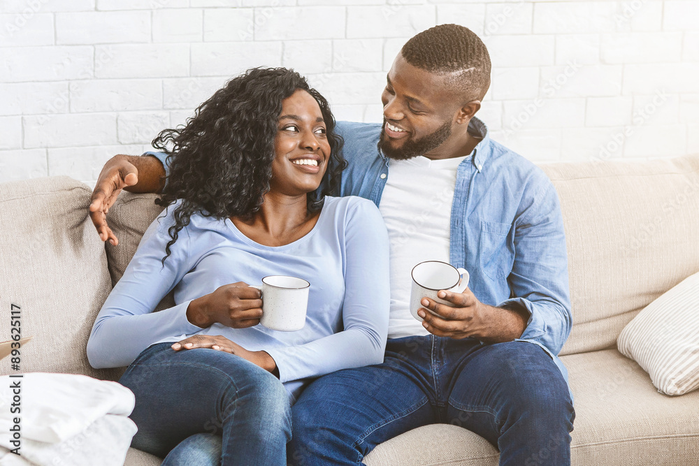 New beginning with new apartment. Afro young couple in love sitting on sofa at new house, planning future together
