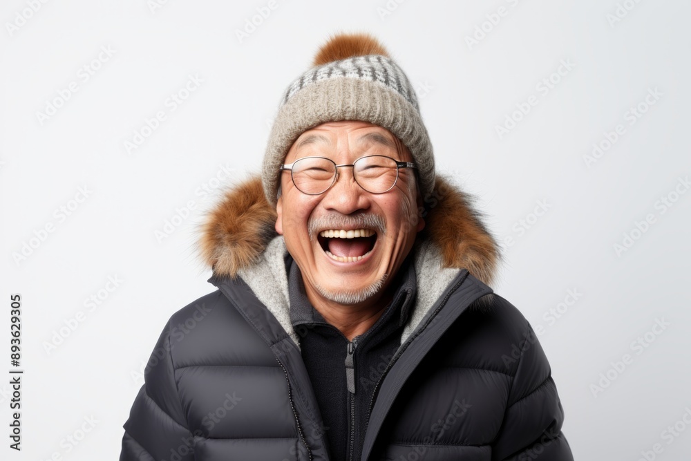 Portrait of a joyful asian man in his 60s dressed in a warm ski hat in front of white background