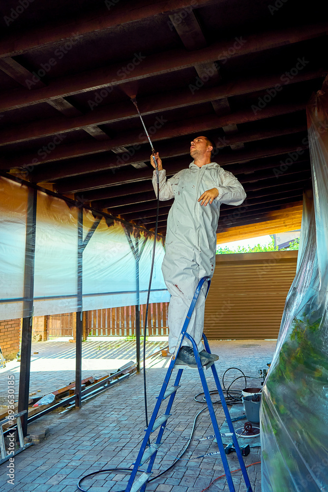 Fototapeta premium man paints a room with a spray gun