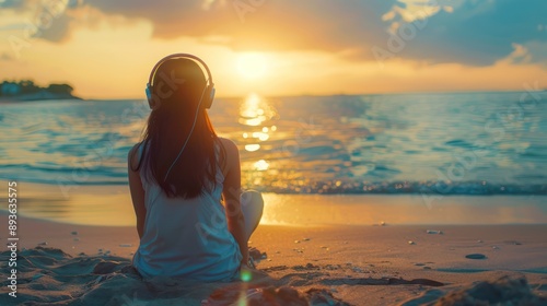 A young girl sitting on the beach, wearing headphones