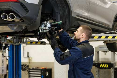 Brake pad repair, car on a lift, close-up. A modern car in a car service on a lift with a wheel removed. Elements of the brake system and suspension