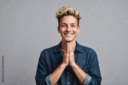 Portrait of Non binary person standing over isolated background with hands together and crossed fingers smiling relaxed and cheerful. success and optimistic photo