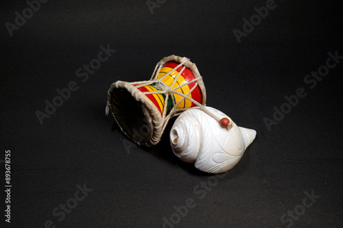 White musical conch and damru on black background