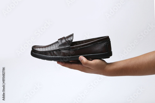 leather loafers slip on shoes holding in hand on light background