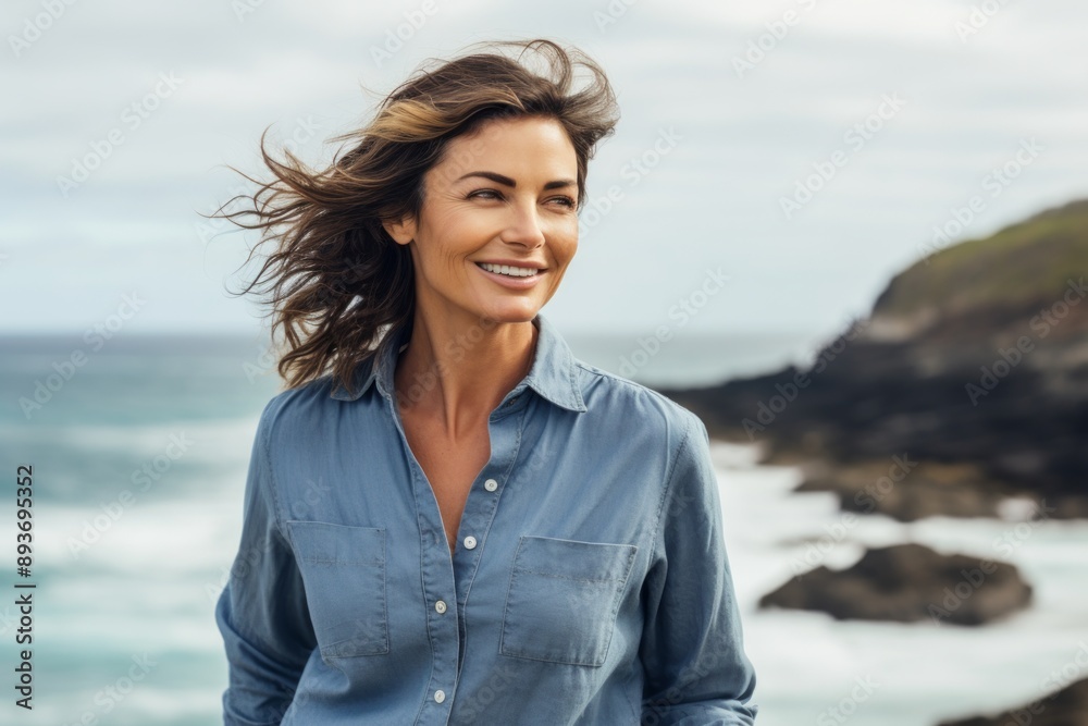 Portrait of a blissful woman in her 40s sporting a versatile denim shirt in front of stunning ocean reef Portrait of a blissful woman in her 40s sporting a versatile denim shirt in front of stunning ocean reef
