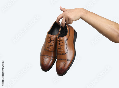 Foto tan leather oxford brogue shoes hold in hand isolated on white background