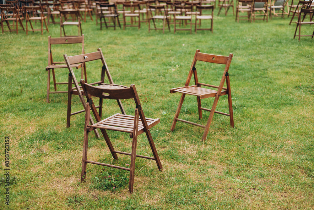 Wooden chairs for outdoor shows. Rows of empty chairs in a public park. Comfortable on outdoor patio chairs in garden. Ceremony or concert in the garden. Selective focus. Wooden chairs for outdoor shows. Rows of empty chairs in a public park. Comfortable on outdoor patio chairs in garden. Ceremony or concert in the garden. Selective focus.