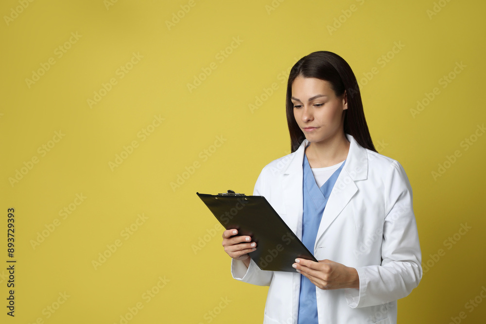 Portrait of beautiful nurse with clipboard on yellow background. Space for text Portrait of beautiful nurse with clipboard on yellow background. Space for text