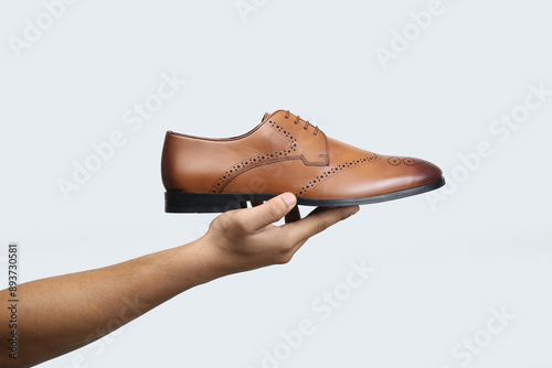 Canvas Print tan leather oxford brogue shoes hold in hand isolated on white background