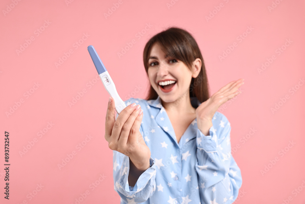 Happy young woman with pregnancy test on pink background Happy young woman with pregnancy test on pink background