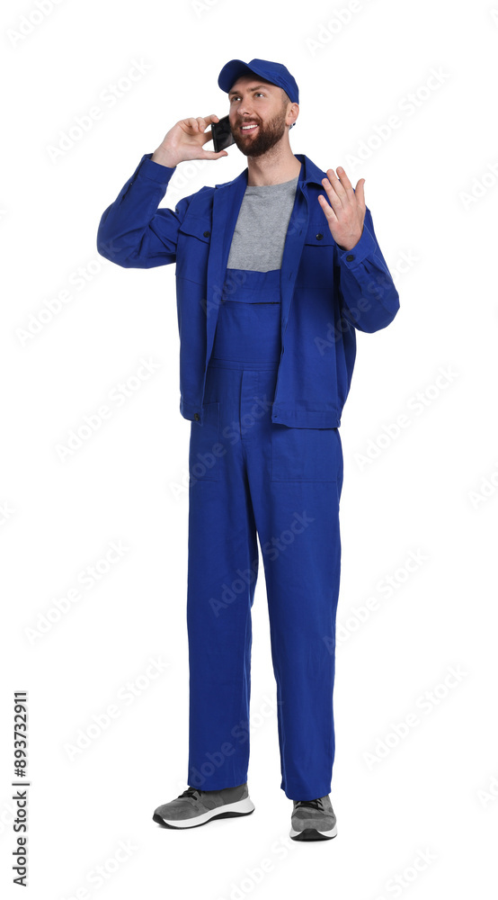 Professional auto mechanic talking on phone against white background Professional auto mechanic talking on phone against white background