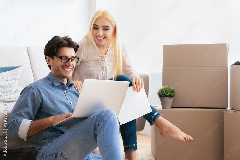 A couple sits on the floor in their new home, surrounded by boxes, with one using a laptop while the other looks on. A couple sits on the floor in their new home, surrounded by boxes, with one using a laptop while the other looks on.