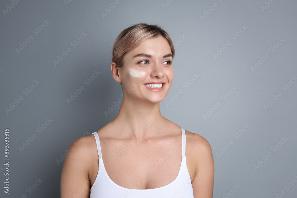 Beautiful woman with cream on her face against gray background Beautiful woman with cream on her face against gray background