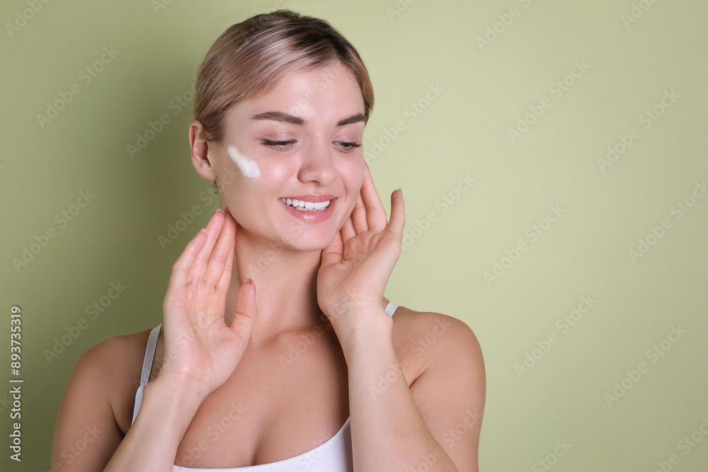 Beautiful woman with cream on her face against light green background, space for text Beautiful woman with cream on her face against light green background, space for text