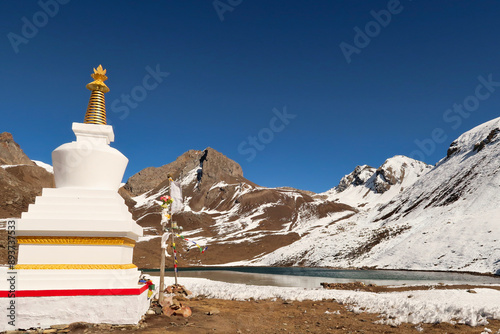 A buddhist stupa, pagoda in front of the Ice Lake, Kicho Tal, Khicho Ice Lake on a sunny day, close to Manang, Annapurna Circuit Trek, Nepal photo