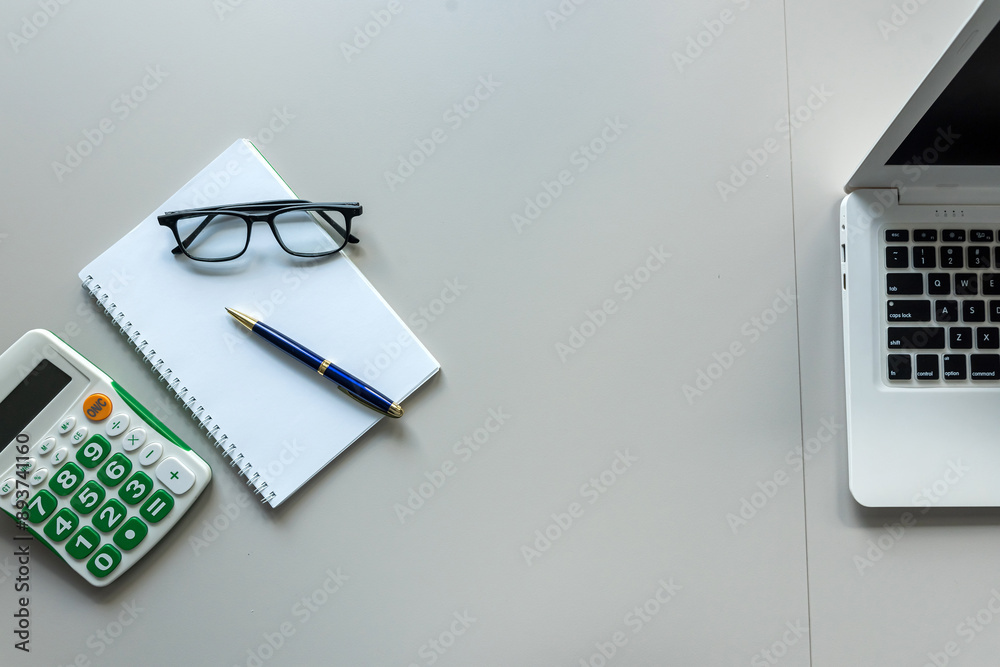 White office desk with laptop blank notepad calculator and pen eyeglasses White office desk with laptop blank notepad calculator and pen eyeglasses