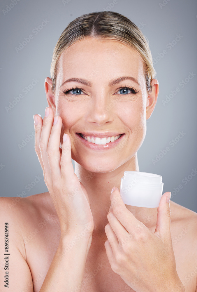 Happy woman, portrait and face cream with container in skincare or moisturizer on a gray studio background. Young female person or model with smile for facial ointment, lotion or anti aging cosmetics Happy woman, portrait and face cream with container in skincare or moisturizer on a gray studio background. Young female person or model with smile for facial ointment, lotion or anti aging cosmetics