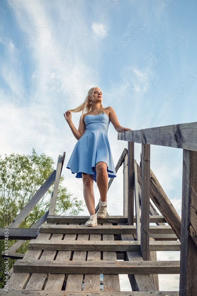 A girl in a blue dress stands on a wooden bridge. A girl in a blue dress stands on a wooden bridge.