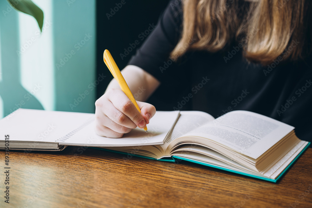 Young woman studying with a book and pen at a table Young woman studying with a book and pen at a table