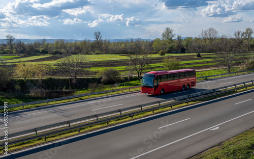 Red Modern comfortable tourist bus driving through highway at bright sunny sunset. Travel and coach tourism concept. Trip and journey by vehicle
 photo