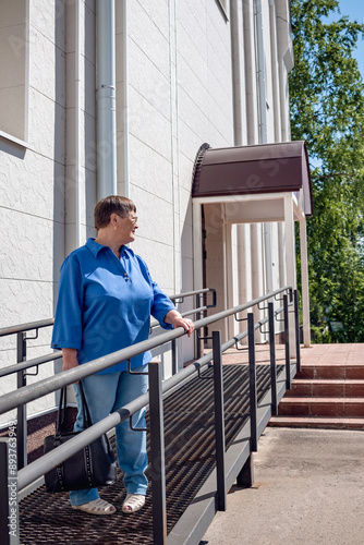 An elderly woman stands at the entrance of a white Orthodox church.