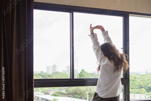 A young woman stood by the window in the morning after waking up to admire the view and atmosphere of the resort the morning after she had rested all night. Refreshing concept after waking up Free Download A young woman stood by the window in the morning after waking up to admire the view and atmosphere of the resort the morning after she had rested all night. Refreshing concept after waking up - GFXLoad